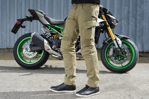 Side view of rider with 4SR Tourismo Green motorcycle jeans and textile RTX jacket, next to motorcycle