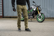 Close front view of rider standing with 4SR Tourismo Green motorcycle jeans paired with textile RTX jacket
