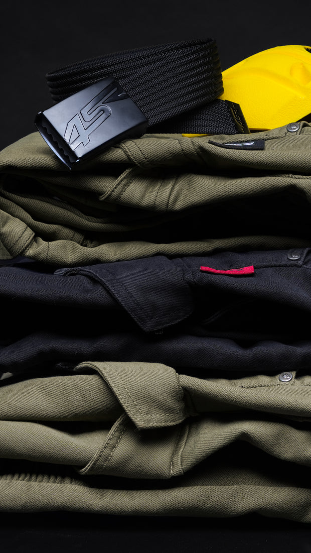 Stack of folded 4SR Tourismo motorcycle jeans in green and black with black 4SR belt and yellow Safe Tech protector on top.