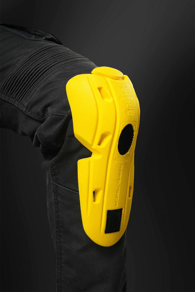 Yellow Safe Tech Level 2T+ knee protector positioned on black 4SR Tourismo jeans knee area, highlighting ergonomic shaping and shin coverage.