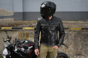 Rider wearing 4SR Scrambler Petroleum II black leather jacket with Level 2 protectors, standing by Ducati motorcycle